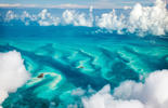 Aerial view of a turquoise sea below clouds_Adobestock